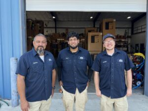 Three Barker's Technicians Standing Together in Front of Shop