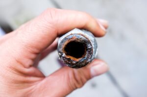 corroded pipe being held by plumber hand