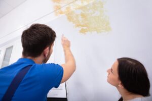 plumber and homeowner looking up at a water leak stain in college station home